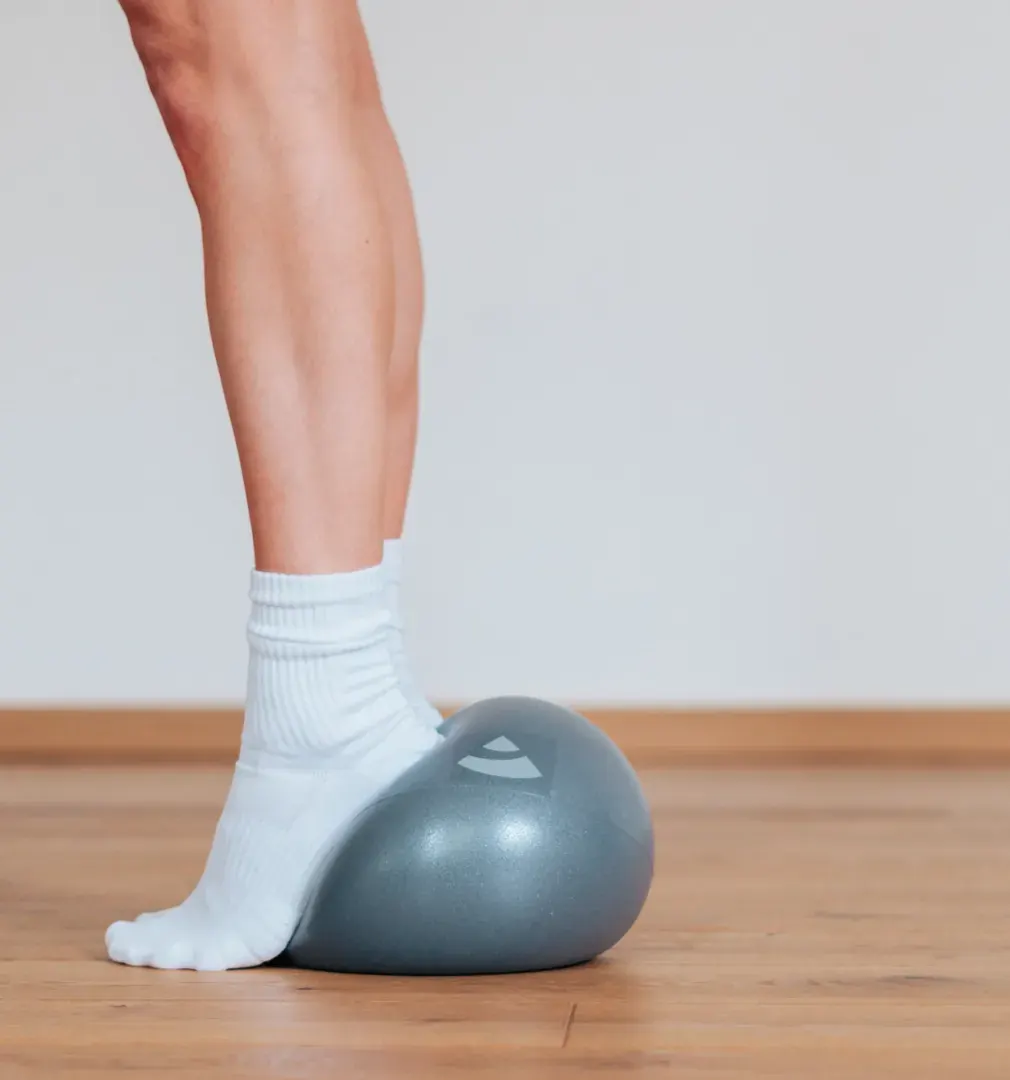 Fuß auf einem kleinen Pilatesball – Balance-Übung im Barre-Training